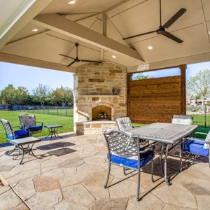 Covered patio with lights and fans over a stone fireplace